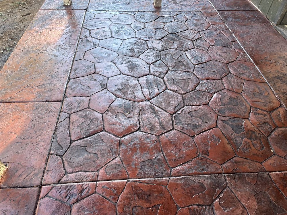 Close view of finished colored concrete with a decorative random-stone pattern and textured border.