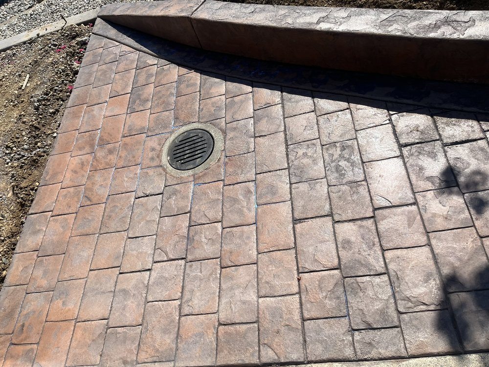 Stamped concrete surface shaped around an integrated drain